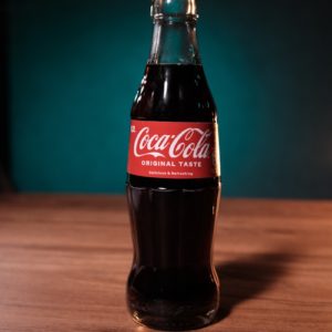 a bottle of coca cola sitting on top of a wooden table